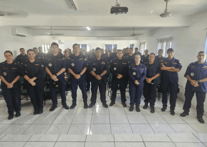 Grupo de pessoas em uniformes no auditório.