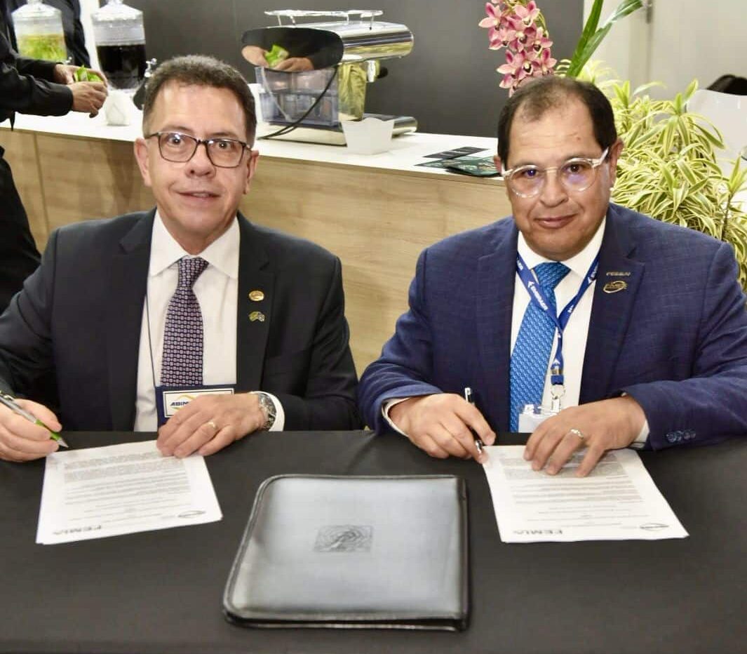 Dois homens assinando documentos em evento empresarial.