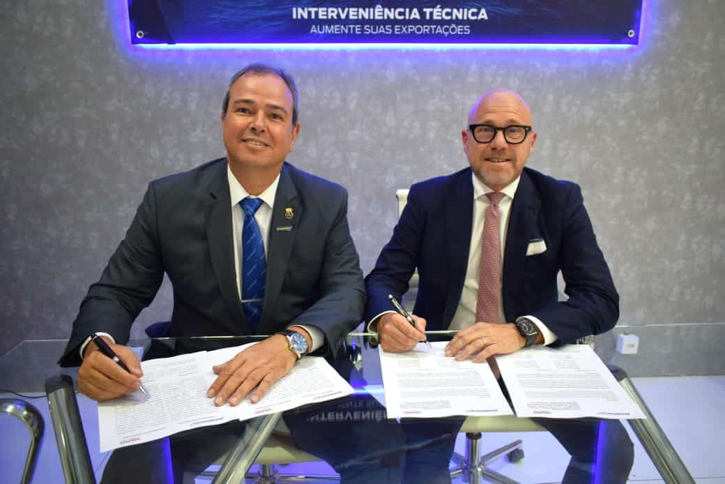 Dois homens firmando documentos em escritório moderno.