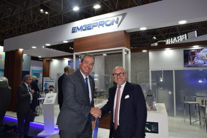 Dois homens apertam as mãos em stand da EMGEPRON.