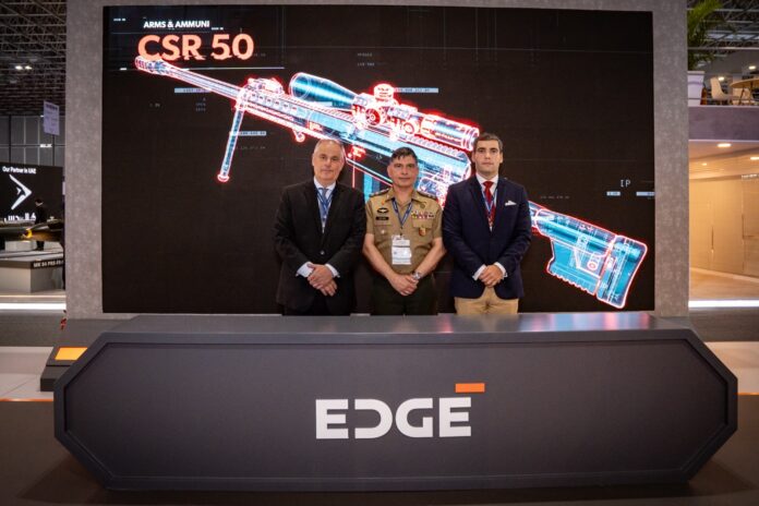 Três homens em frente ao display de arma CSR 50.