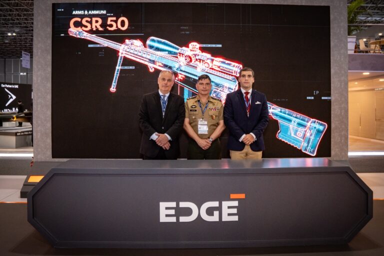 Três homens em frente ao display de arma CSR 50.