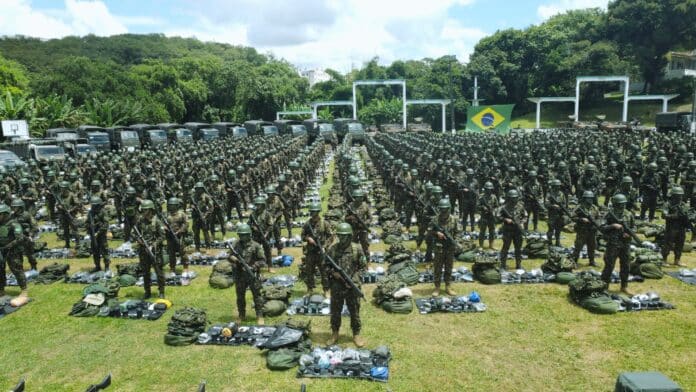 Soldados do exército alinhados com bandeira do Brasil.