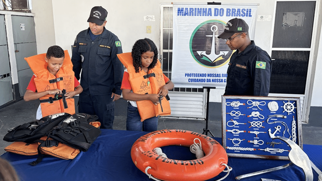 Crianças aprendem com marinheiros sobre segurança marítima.