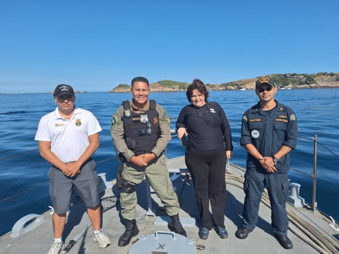 Quatro pessoas uniformizadas em barco no mar.