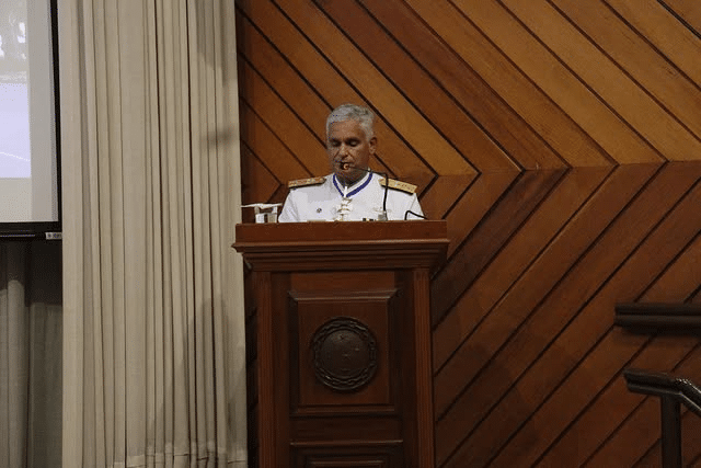 Oficial discursando em pódio de madeira.