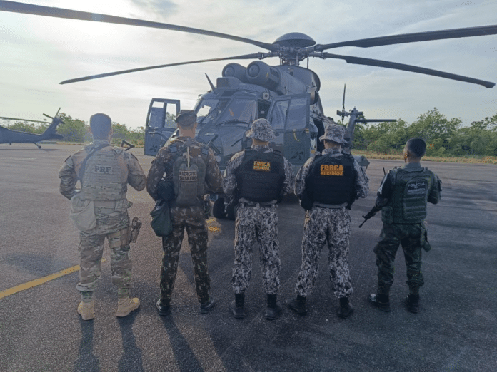 Militares brasileiros em frente a helicóptero estacionado.