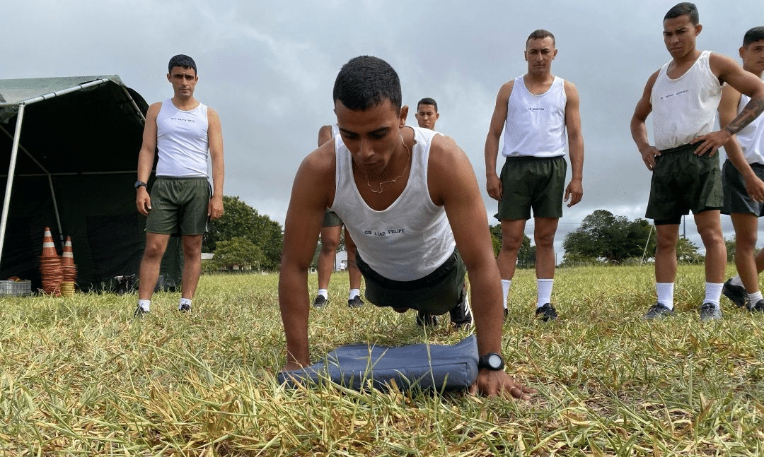 Soldados treinando flexões ao ar livre.