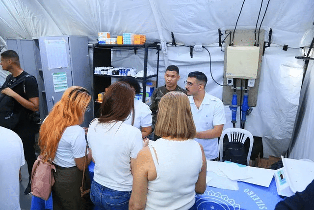 Atendimento médico em tenda improvisada com profissionais.