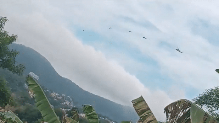 Helicópteros sobrevoando montanhas e vegetação tropical.