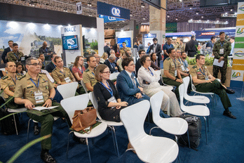 Pessoas assistindo palestra em conferência militar.