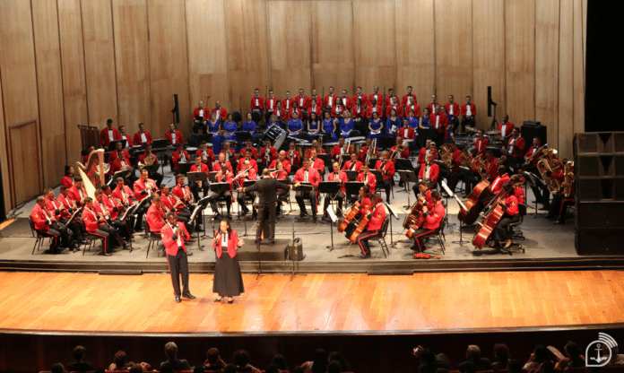 Orquestra sinfônica em apresentação no palco.