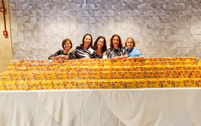 Cinco pessoas atrás de caixas de panetone.