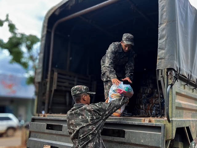 Soldados distribuem suprimentos em caminhão militar.
