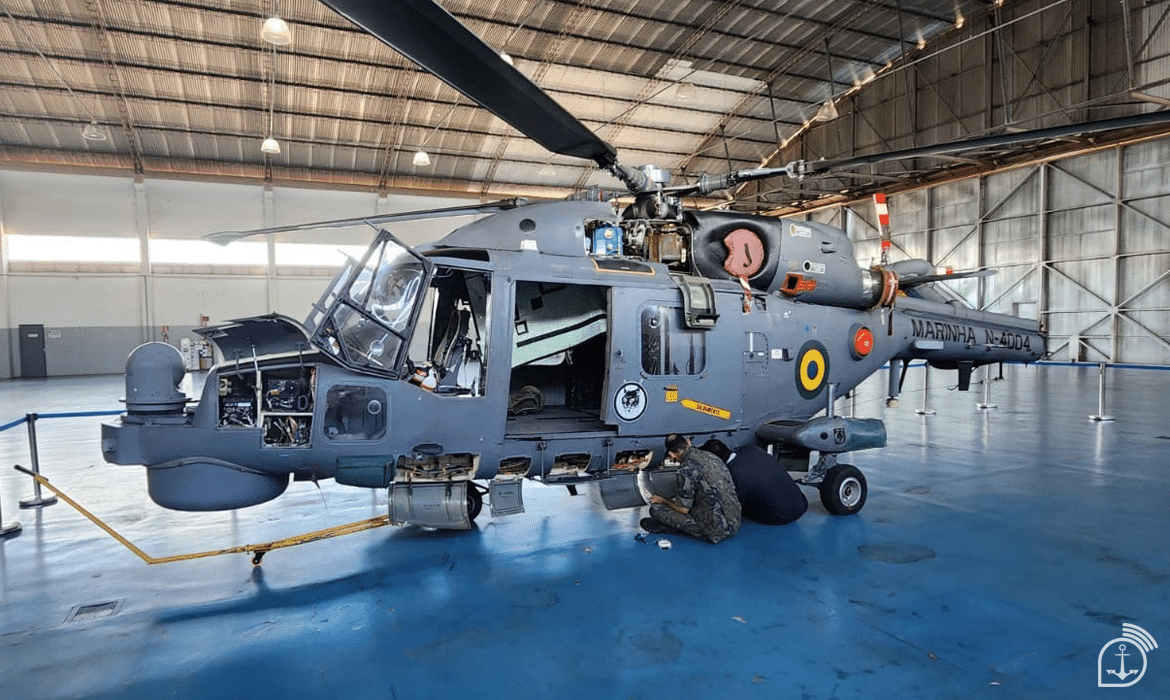 Manutenção de helicóptero militar em hangar.