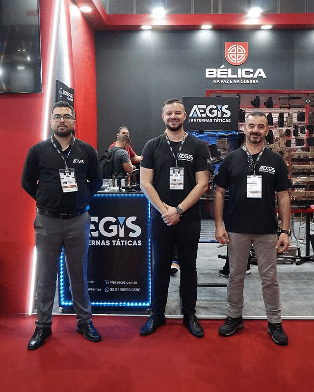 Equipe exibe lanternas táticas em feira de segurança.