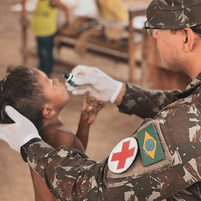 Militar aplica medicamento oral em criança.