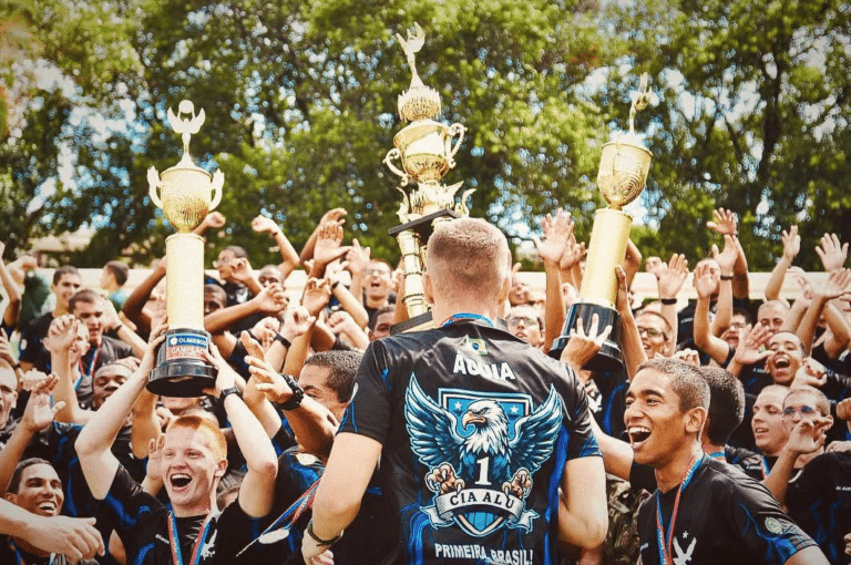 Time comemora vitória com troféus ao ar livre.