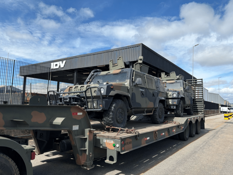 Veículos militares em carreta na frente de IDV.