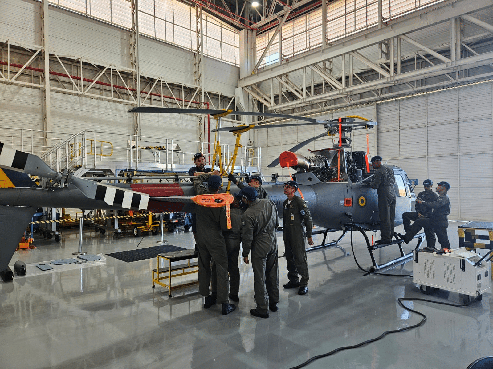 Equipe manutenção de helicóptero em hangar.