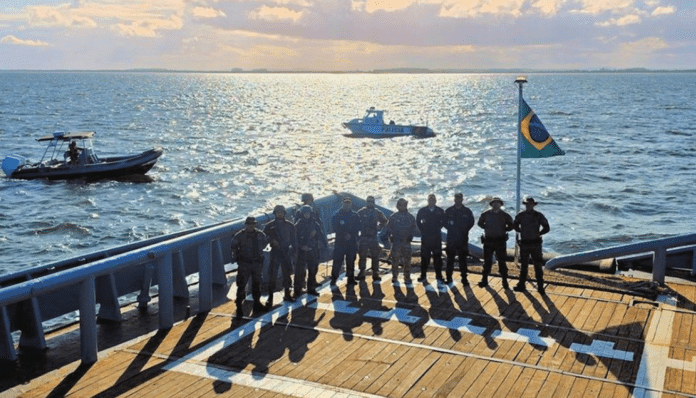 Equipe policial em barco com bandeira do Brasil.