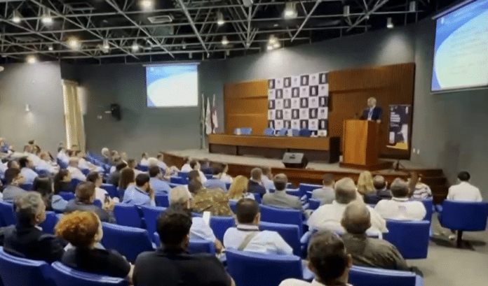 Palestrante apresenta para plateia em auditório.