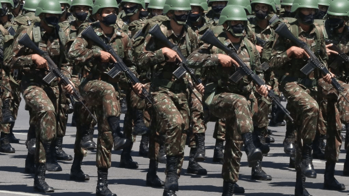 Soldados marcham em uniforme militar camuflado.