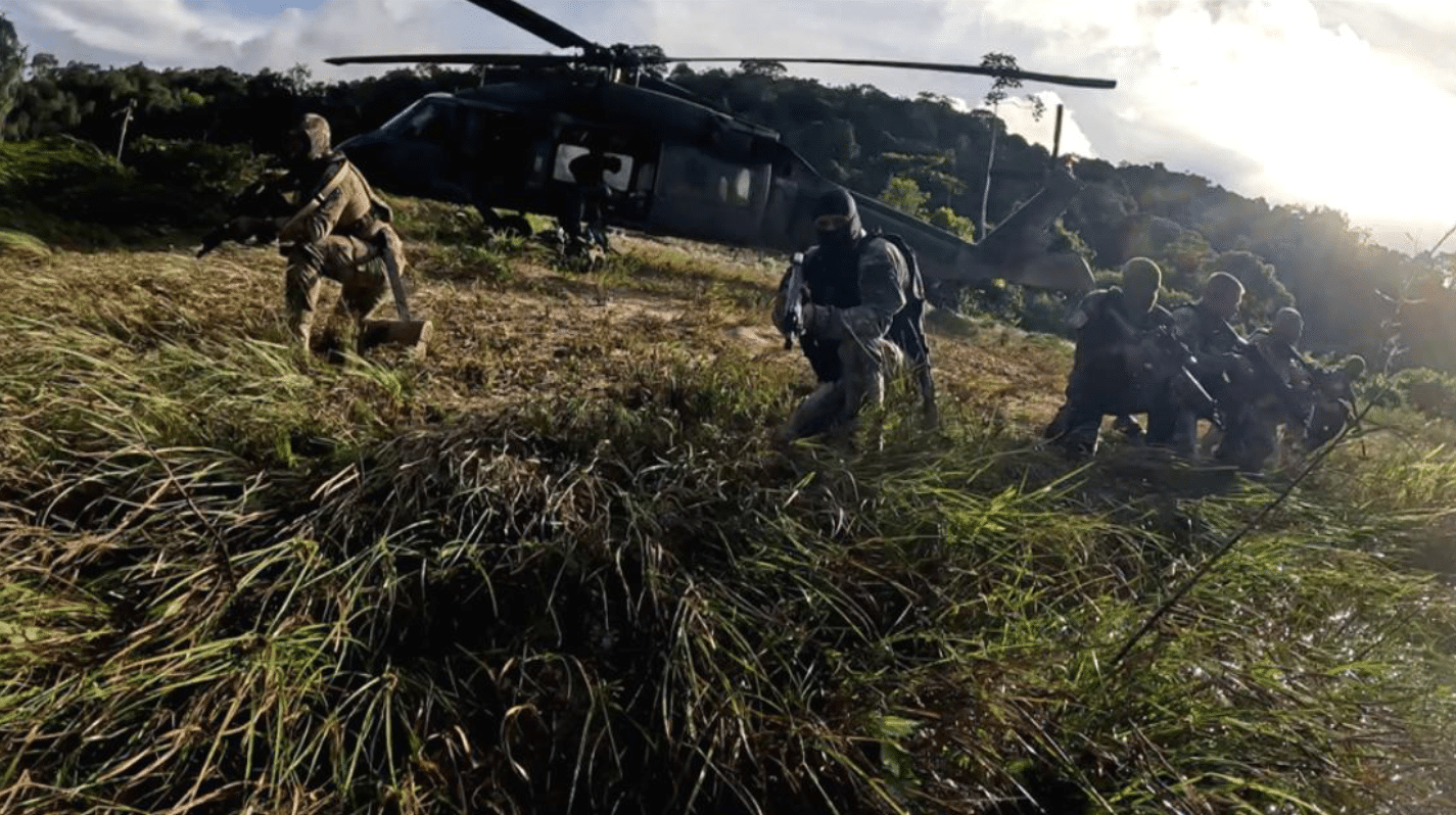 Soldados em exercício com helicóptero no campo.