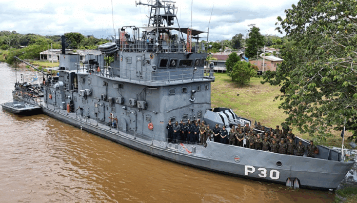 Navio militar P30 navegando em rio com tripulação a bordo.