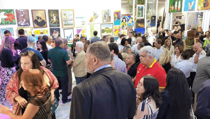 Exposição de arte com muitos visitantes admirando as obras.