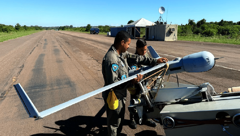 Soldados preparando drone em pista de aviação.