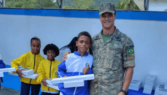 Soldado entrega tablets a estudantes em evento comunitário.