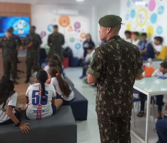 Militares palestram para crianças em sala colorida.