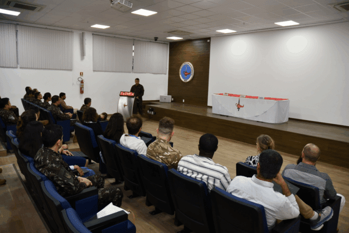 Palestra militar em auditório com público atento.