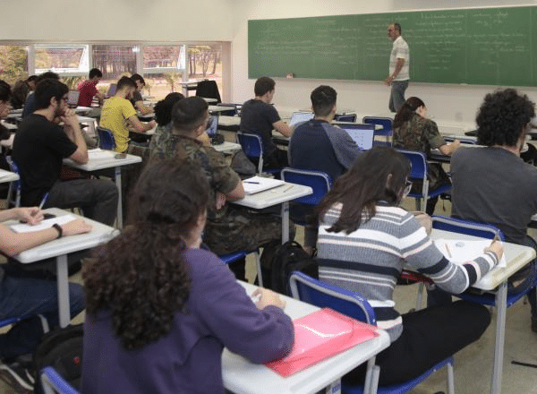 Estudantes em aula com professor escrevendo no quadro