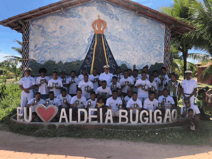 Grupo com placas, aldeia Bugigão ao fundo.