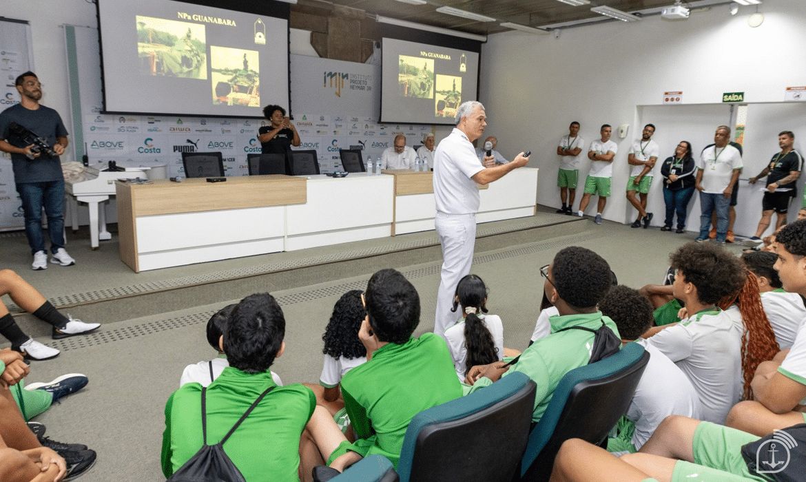 Palestrante falando para estudantes em auditório.