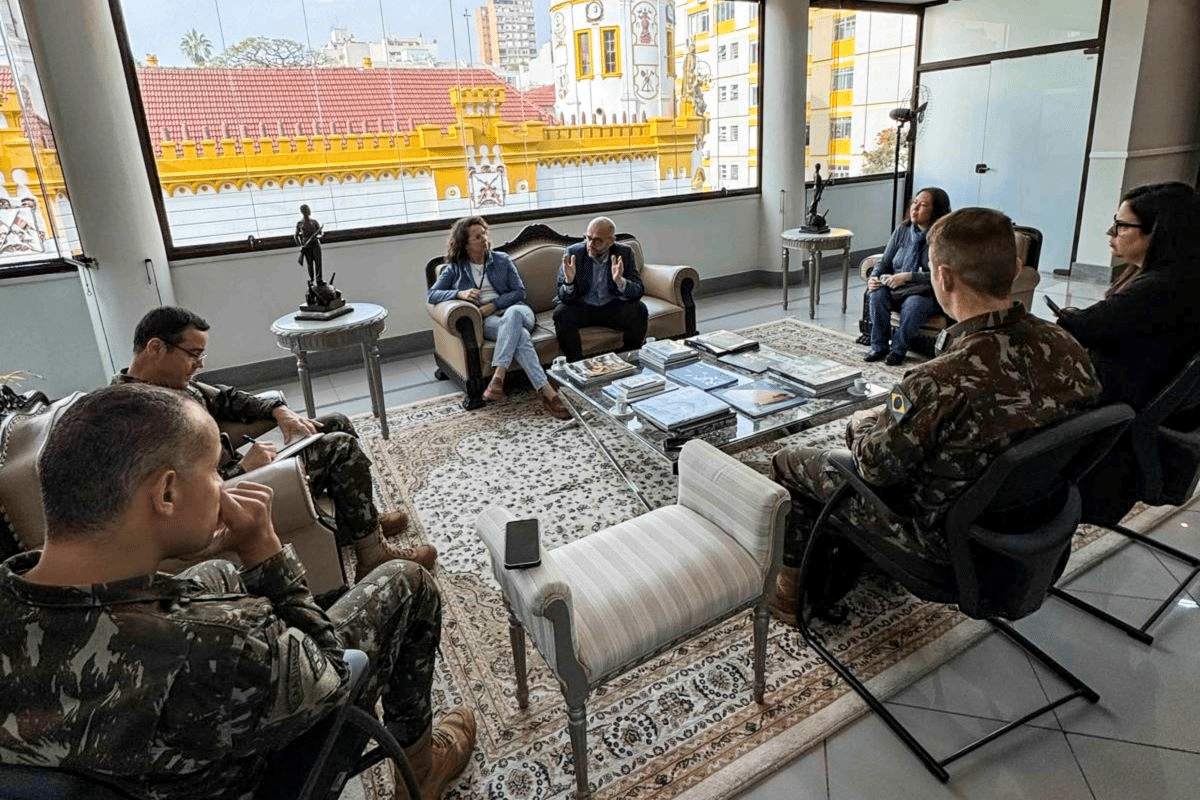 Reunião em sala com militares em uniforme camuflado.