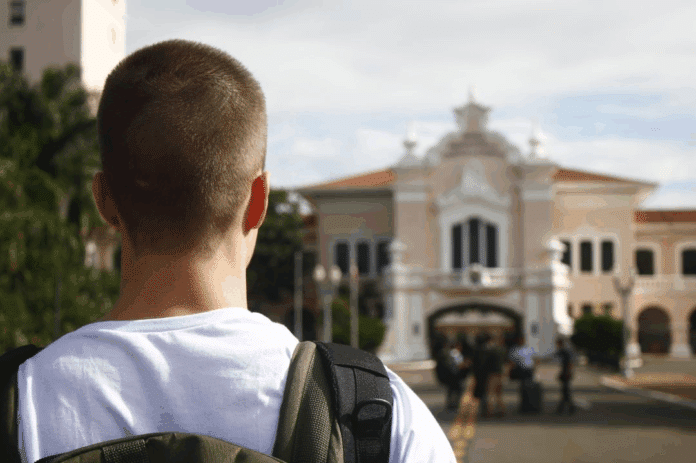 Pessoa de mochila olhando para prédio histórico.
