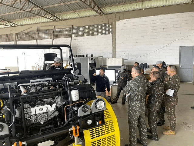Militares em treinamento com veículo em oficina.