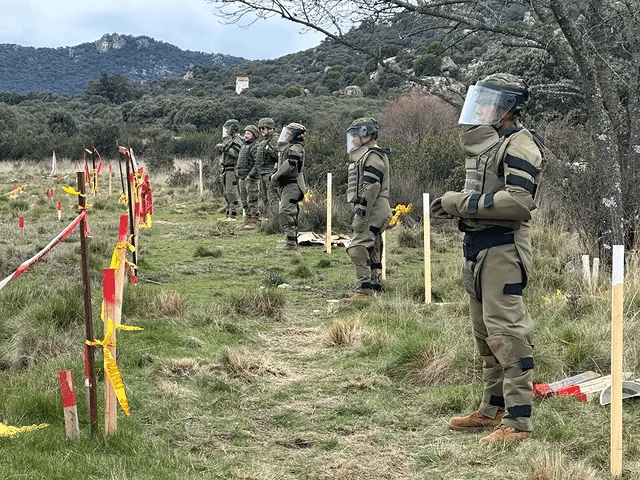 Soldados em campo de treinamento com equipamento de segurança.