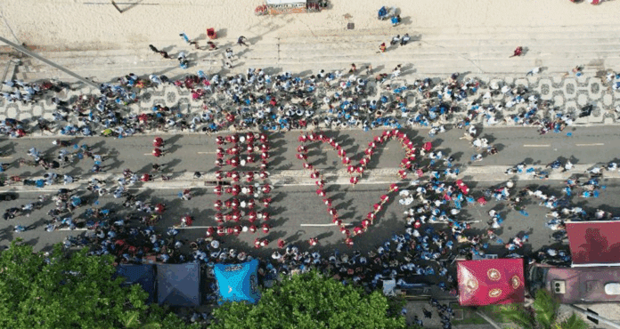Desfile na praia formando 'EU ❤️'.
