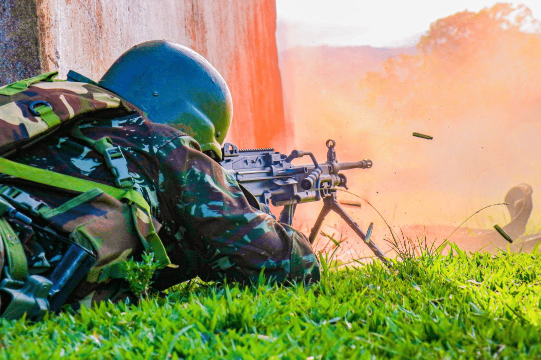 Soldado camuflado com metralhadora em ação.