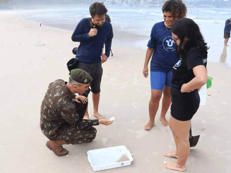 Militar e pesquisadores analisam praia para coleta de sedimentos.