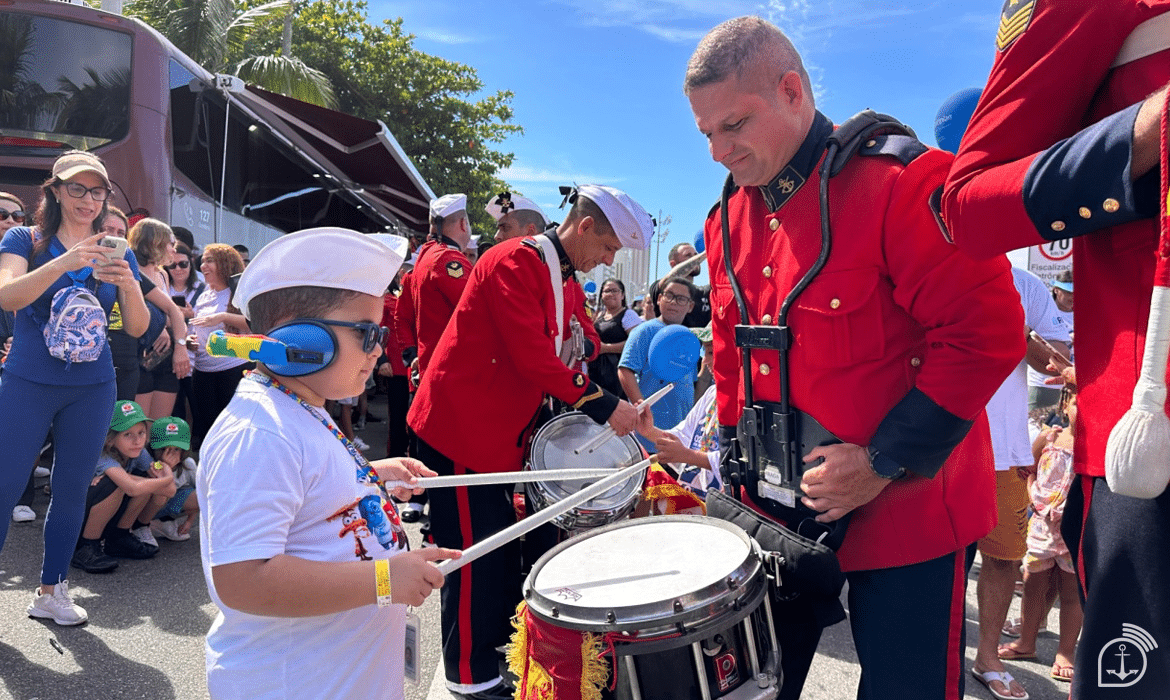 Criança toca tambor com banda em desfile.
