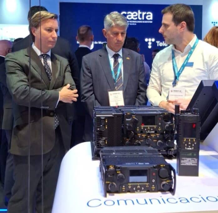 Homens observam equipamentos de comunicação em exposição.