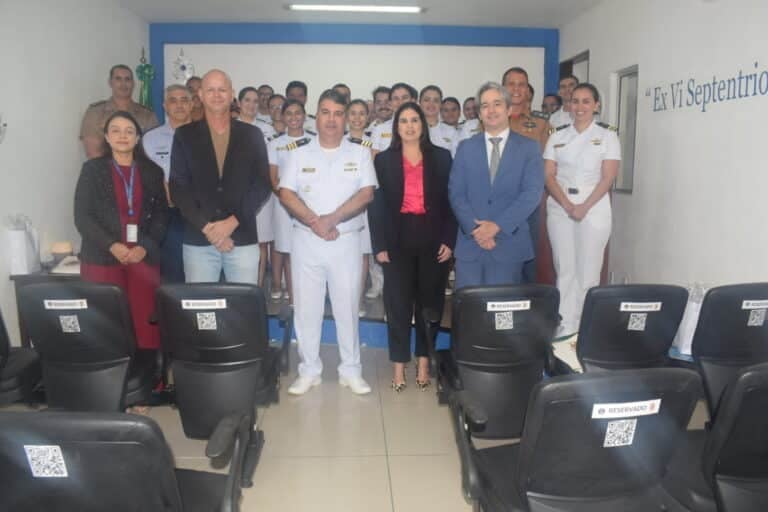 Grupo de pessoas em ambiente formal com cadeiras vazias.