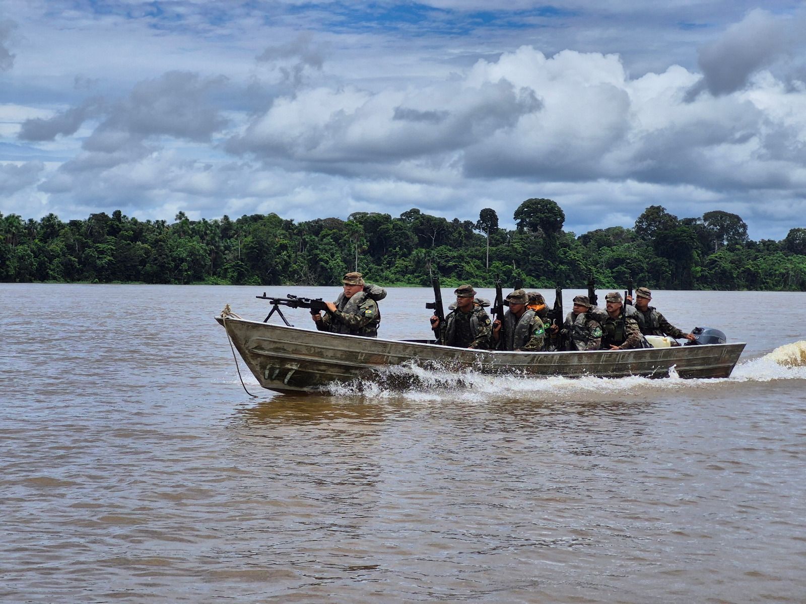 Militares em barco patrulhando rio na selva.