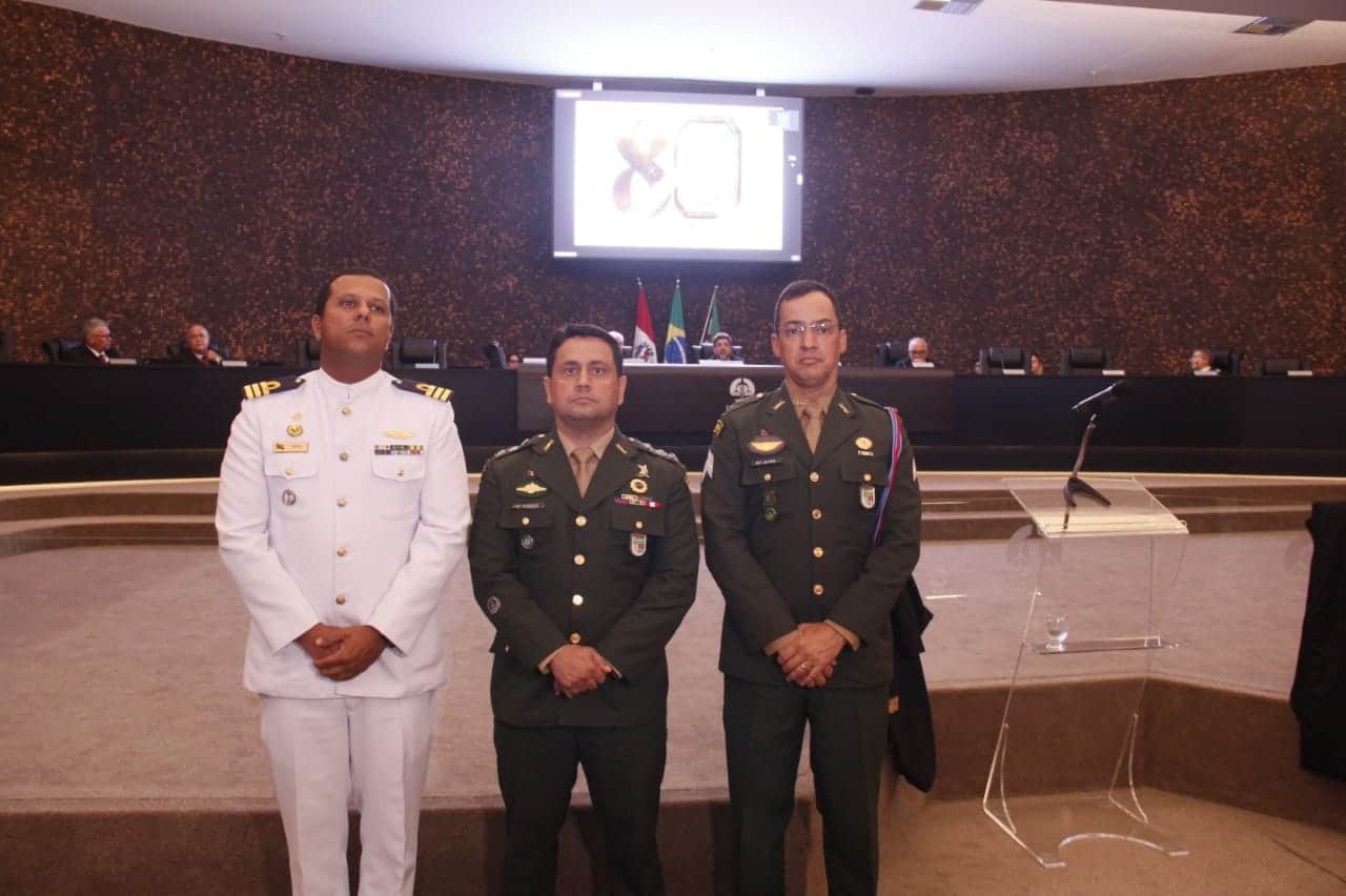 Militares em cerimônia oficial, tribunal ao fundo.