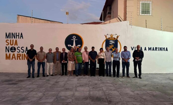 Grupo de pessoas em frente a mural da Marinha.